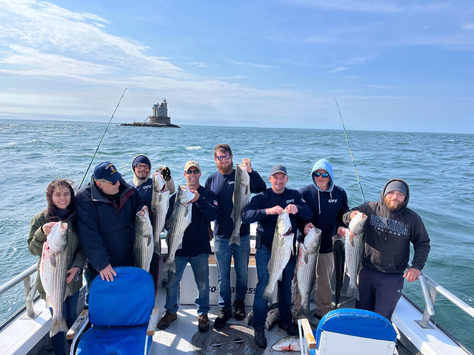 The Outdoor Property Services crew on the boat off Race Rock Light, every one holding up a striped bass