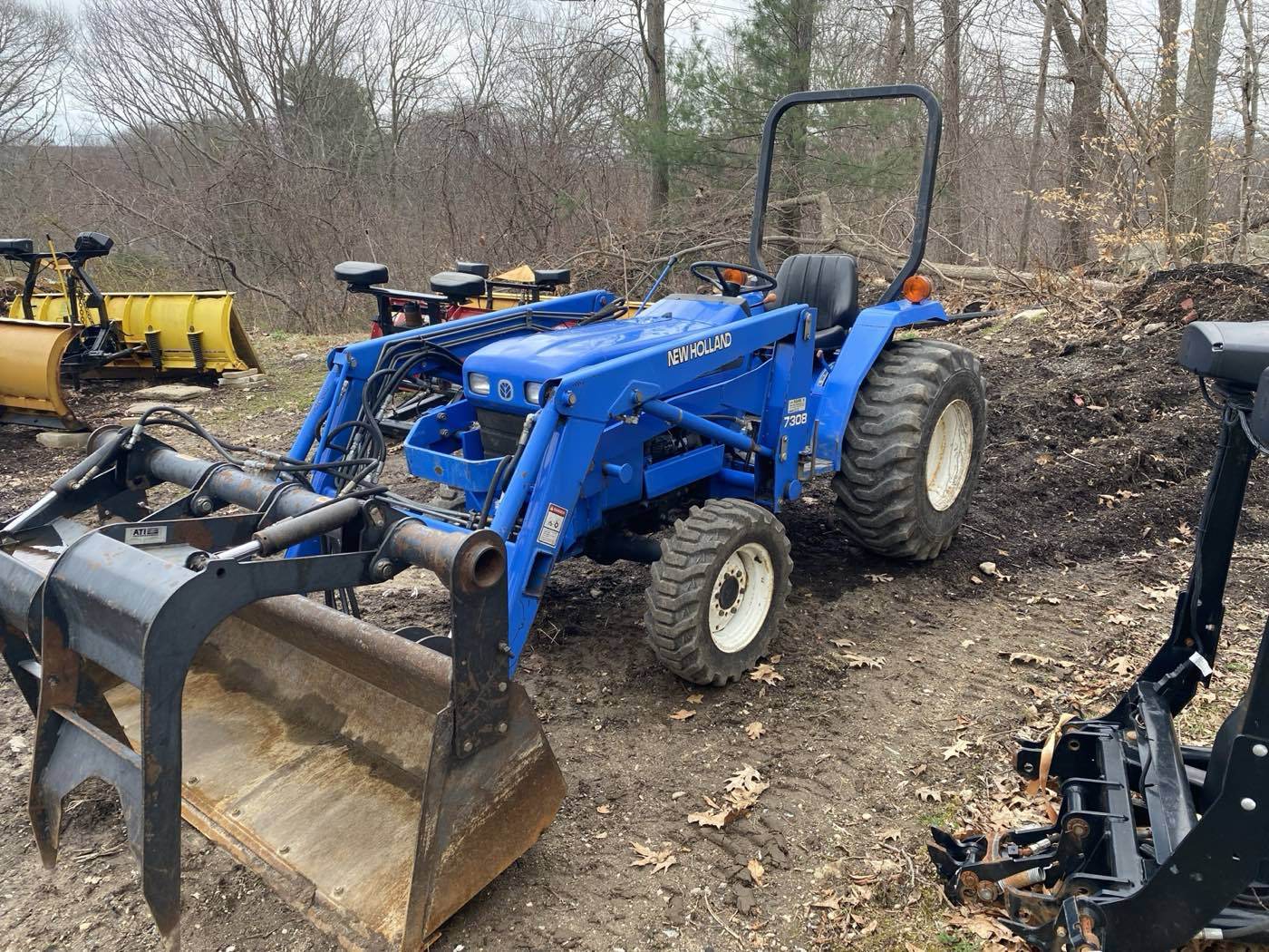 The Outdoor Property Services New Holland tractor carrying the loader bucket and grapple used for heavy clearing work