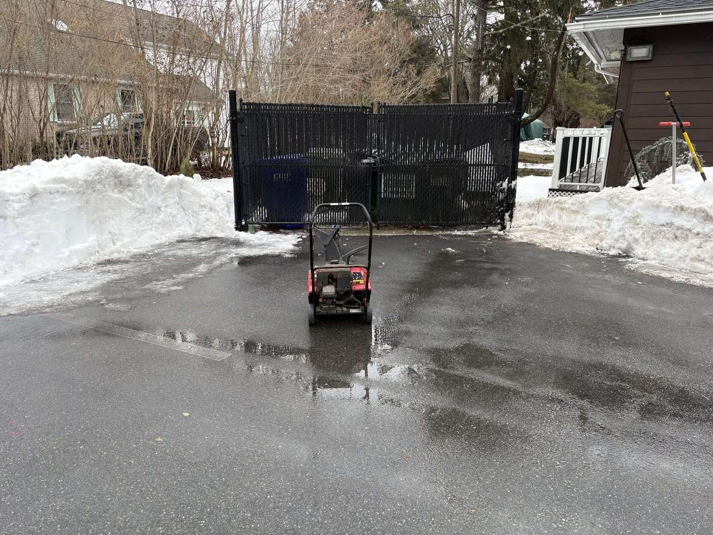 A walk-behind snow machine finishing a paved area cleared to blacktop in southeastern Connecticut