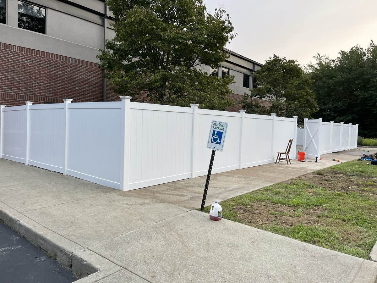A run of white vinyl privacy panels set along the side of a commercial building in southeastern Connecticut by Outdoor Property Services