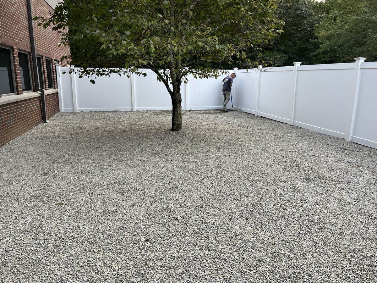A new gravel yard raked out and screened with white vinyl panels at a commercial building in southeastern Connecticut