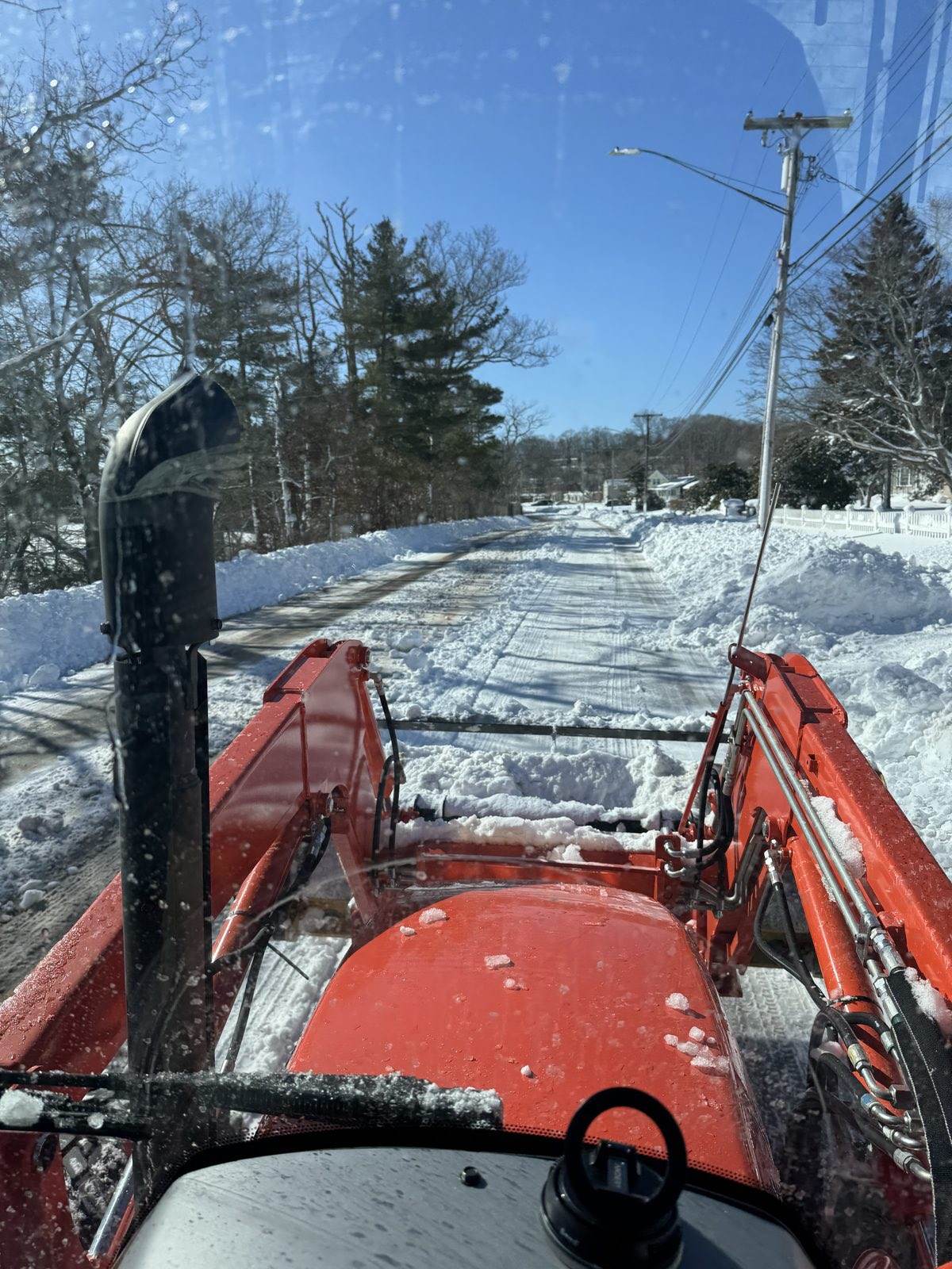 A long private drive in southeastern Connecticut plowed out by an Outdoor Property Services tractor and banked with snow either side