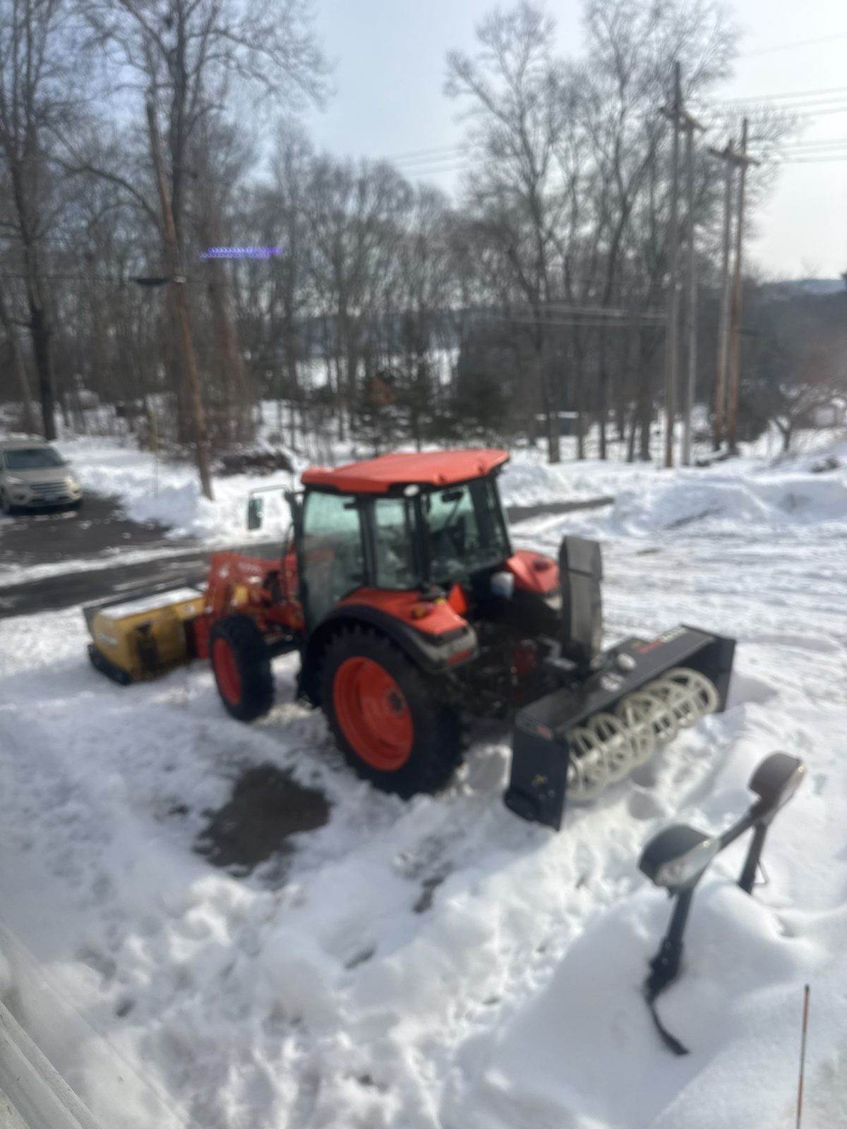 An Outdoor Property Services tractor carrying a front plow and a rear snowblower, working deep snow at a roadside in southeastern Connecticut
